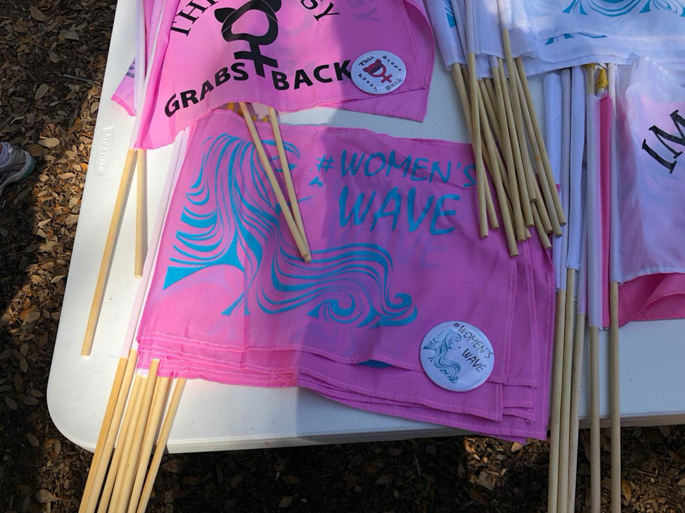 Figure 2. Image showing #womenswave appearing on merchandise (flags and a button) for sale at Lake Eola Park on Jan. 19, 2019.