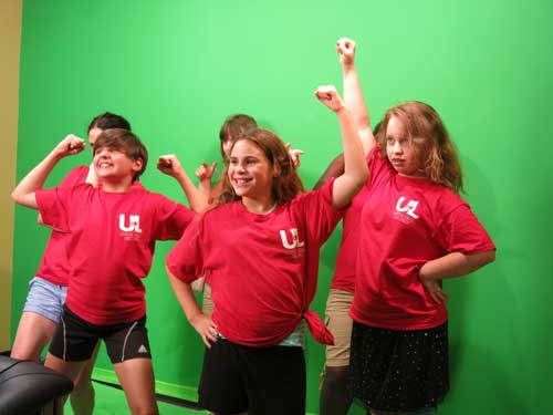 A group of girls strikes powerful poses in the greenscreen room