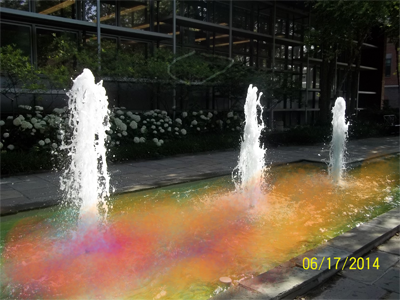 A picture of a fountain, edited to have rainbow-colored water