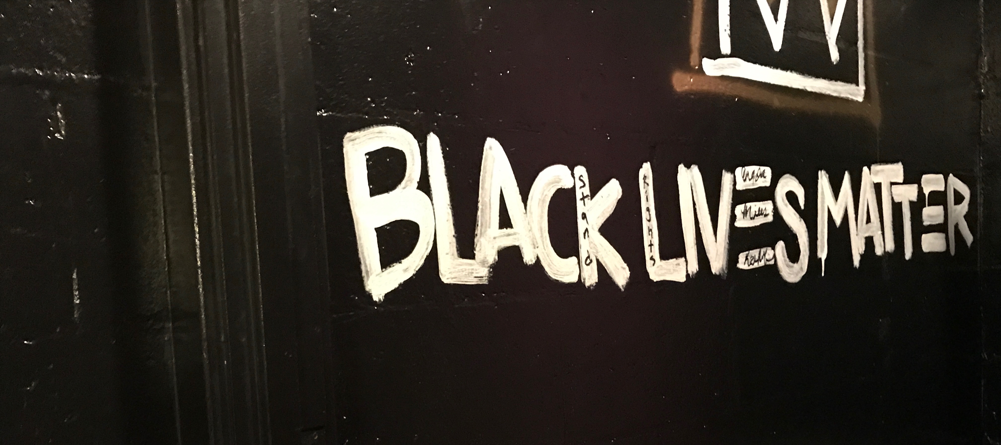 a black wall painted in white with the words Black Lives Matter