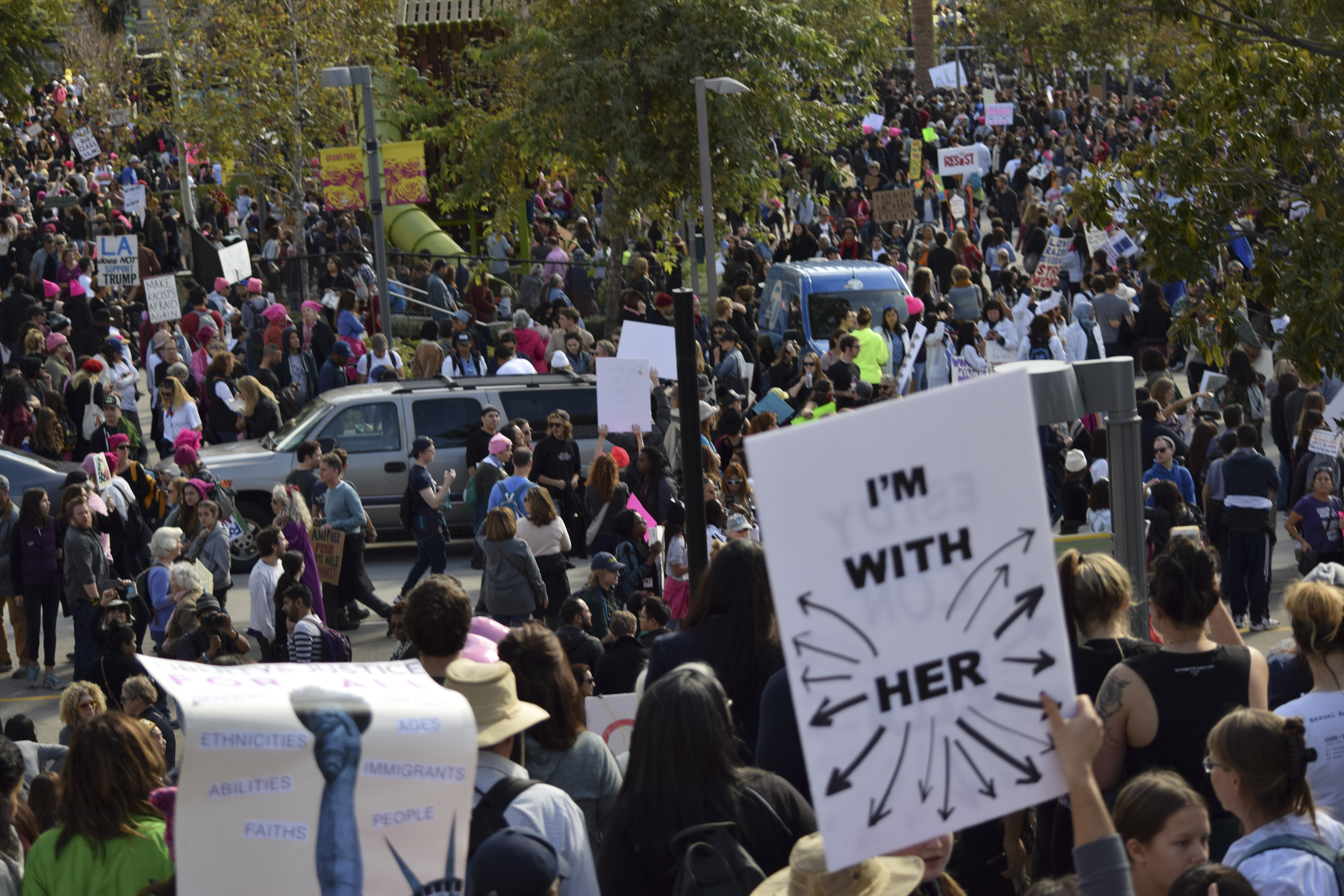 an image of a crowd of protesters at the Women's March. In the foreground one protester holds a sign saying I'm With Her, with arrows pointing in every direction to indicate fellow protesters