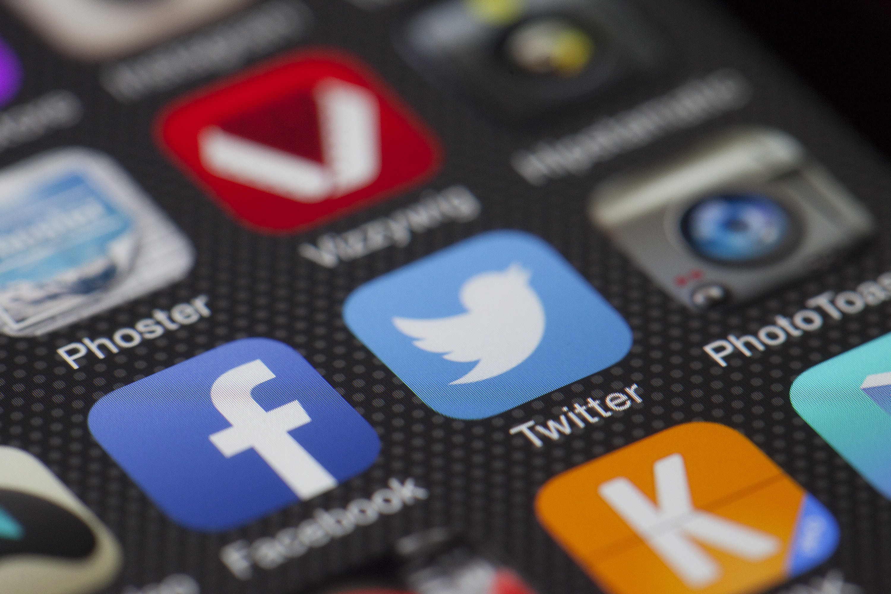 Image of a zoomed-in smartphone screen with blurry social media icons, including Facebook and Twitter.